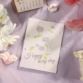 Elegante tarjeta de felicitación floral con texto Happy every day sobre fondo de tela lila. - Estilo 9