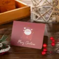 Detailed view of a burgundy Christmas card with gold foil Santa Claus illustration. - Santa Claus / 10 Sheets Set