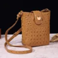 Detalle de un bolso bandolera vintage marrón con relieve de cocodrilo de calidad - Tostado