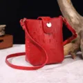 Primer plano de bolso bandolera rojo vintage con textura de cocodrillo y cierre dorado - Rosa rojo