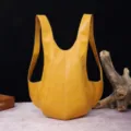 Vista detallada de una mochila vintage de cuero amarillo en forma de escarabajo con curvas - Amarillo