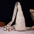 Elegante bolso bandolera retro crema con correa bordada bohemia sobre fondo de madera rústica. - Bolso de Pecho Retro (PG812) / Blanco Roto