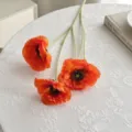 Amapolas artificiales naranjas con tallos flocados sobre un mantel de encaje blanco - Naranja