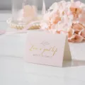 Primer plano de una tarjeta rosa doblada con texto dorado 'Live a good life' decorativa - Live Well Meet Slowly