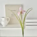 Pink artificial iris flower stem with green leaves in a minimalist home decor setting - Pink