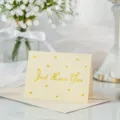 Detalle de tarjeta de felicitación crema con texto Just Love You en pan de oro y corazones - Solo Te Amo