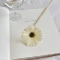 Elegant white PU artificial gerbera daisy flower displayed on an open white book - Milk White