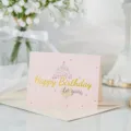 Elegante tarjeta de felicitación rosa con texto Happy Birthday dorado y su sobre - Feliz cumpleaños