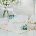 Tarjeta de felicitación dorada con hojas de eucalipto verdes y un mensaje motivador. - El Niño Más Feliz Del Universo