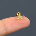 Close-up detail of a delicate gold flower stud earring with clear CZ stones on a finger. - Five-Petal Flower Shape (S-CC135-2) / Gold