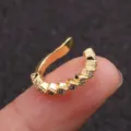 Close-up of small gold ear cuff inlaid with clear zircon stones on finger - Eight-Stone Open Cuff (KAE297-2-2) / Gold