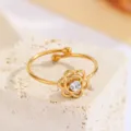 Detailansicht eines eleganten goldenen Blumenrings mit einem funkelnden Kristall - Hohles Blumen-Stil (CXR946-J)