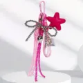 Vista dettagliata del portachiavi rosa con stella, fiocco di perle e ciondolo a cuore. - Rosa
