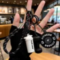 Dettaglio del portachiavi fitness con ciondoli in miniatura a forma di manubrio e shaker. - Nero