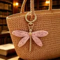 Primo piano del ciondolo portachiavi libellula rosa intrecciato a mano con anello oro. - Rosa