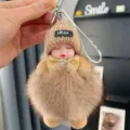 Close-up detail of the cute sleeping doll keychain with fluffy fur ball and rhinestone bow. - Khaki (14cm / 37g)