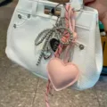 Primo piano dettagliato del grazioso ciondolo portachiavi con fiocco e perline a cuore. - Rosa
