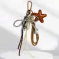 Elegante ciondolo per borsa multi-elemento con fiocco di perline, cuore metallico e stella marina. - Marrone