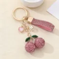 Primo piano del portachiavi a ciliegia in strass con cinturino in pelle rosa e perla. - Rosa
