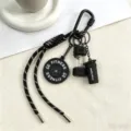 Vista ravvicinata dettagliata del portachiavi fitness nero con piccolo manubrio e shaker. - Nero
