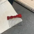 Macro view of a red polka-dot bow hair comb placed on a white fabric with vintage book. - Red Polka Dot