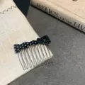 Macro view showing the fine details of a black acetate polka dot bow hair comb accessory. - Black Polka Dot