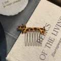 Close-up of a cute leopard print dog acetate hair comb with metal pins on a book - Gold Leopard Print