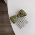 Detail of a green polka dot acetate bow hair insert comb on a white surface - Yellow-Green Polka Dot Comb / Yellow-Green