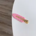 Detailed close-up showing the pink polka dot pattern and golden metal base of this seamless hair clip - Pink