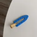 Close-up of blue polka dot seamless hair clip with gold metal base - Blue