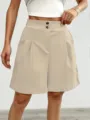 Detailed view of women high waisted pleated beige shorts with front buttons, casual chic. - S / Bottoms / Apricot