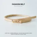 Primo piano di una sottile cintura da donna in pelle PU beige con delicata fibbia metallica. - Giallo Crema / 105cm