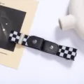 Close-up detail of the black and white checkerboard elastic lazy belt with metal snap. - Black and White Plaid