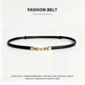 Sottile cintura in pelle nera con fibbia di perle dorate, elegante accessorio femminile. - Nero
