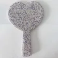 Close-up of a cute heart-shaped rhinestone handheld makeup mirror with glittering crystal gems. - Purple