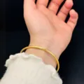 Detailed shot of a minimalist gold-plated titanium steel solid bangle on a wrist - Smooth Bangle (SZ-071) / Width 5mm Diameter 65mm / Gold