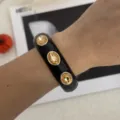 Dettaglio di un bracciale in smalto nero con tre grandi cristalli ambra ovali sul polso. - Stile Strass Geometrico (2557) / nero e oro
