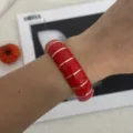Vista dettagliata di un bracciale smaltato rosso con elegante bordo dorato. - Stile Plaid Geometrico (2556) / Rosso