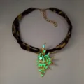 Detailed view of a luminous gold conch shell pendant necklace with leopard strap - Necklace / Gold Green Glow