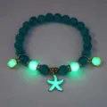 Close-up of glowing starfish charm on turquoise beaded bracelet in dark - Bracelet / Gold (Green Turq Green)
