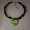 Close-up of luminous sun pendant necklace with leopard print cord and green glow center. - Gold Green Glow Necklace
