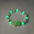Detailopname van een lichtgevende zeesterbedel en een lichtgevende parelarmband in de nacht - Groen Lichtgevende Armband (12#)