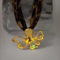 Detailed view of a gold octopus necklace featuring a luminous star and pearls - Gold Orange-Red Glow Necklace
