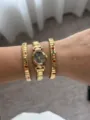 Close-up detail of gold oval watch layered with red heart elastic bracelets on wrist - Gold Set