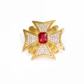 Vintage goudkleurige kruisbroche met rode steen en sprankelende heldere kristallen erop. - Goud