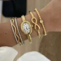 Detailansicht einer goldenen ovalen Uhr, kombiniert mit Infinity- und Perlenarmbändern. - Wave Infinity Watch Bangle Collection (878 Gold)