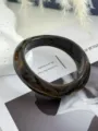 Dettaglio ravvicinato di bracciale quadrato in acrilico con trama marmorea ambra. - Caffè Scuro (1519)