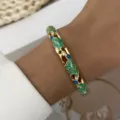 Close-up of gold-plated hollow-out floral bangle with green enamel leaves and crystals - Green And Blue (887-2)