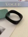 Dettaglio di un bracciale in acrilico nero minimalista con geometria irregolare - Nero