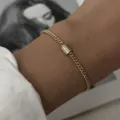 Primer plano detallado de pulsera de cadena dorada con dije de cristal micro-pavé - Cadena Cubana Simple (BR26Y0355)